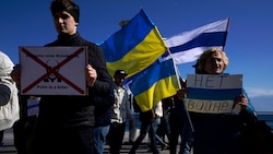 Ukrainer und Russen demonstrieren in Zypern gemeinsam gegen den Krieg und Putin. Die weiß-blau-weiße Flagge ist das Symbol der Antikriegsproteste. (Bild: AP)