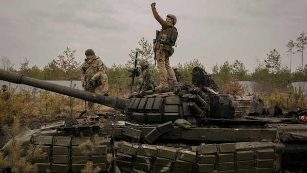 Ukrainische Soldaten auf einem zerstörten russischen Panzer (Bild: AP)