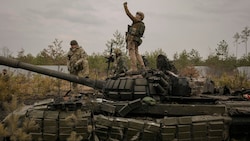 Ukrainische Soldaten auf einem zerstörten russischen Panzer (Bild: AP)