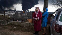 Frauen in Odessa halten sich neben einem Auto auf, während im Hintergrund Rauch aufsteigt. (Bild: The Associated Press)