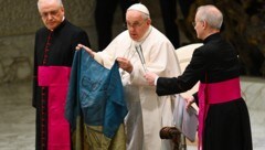 Papst Franziskus mit einer ihm aus Butscha geschickten ukrainischen Flagge (Archivbild) (Bild: AFP)