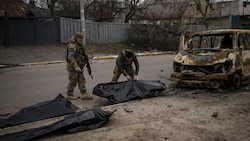 Die Leichen von vier in Butscha getöteten Zivilisten werden von der Straße weggebracht. (Bild: AP)