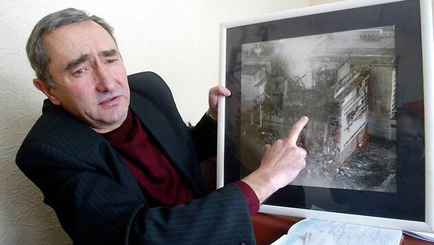 Juri Andrejew mit einem Foto des bei einem Super-GAU zerstörten AKWs Tschernobyl (Archivbild). (Bild: AP/Efrem Lukatsky)
