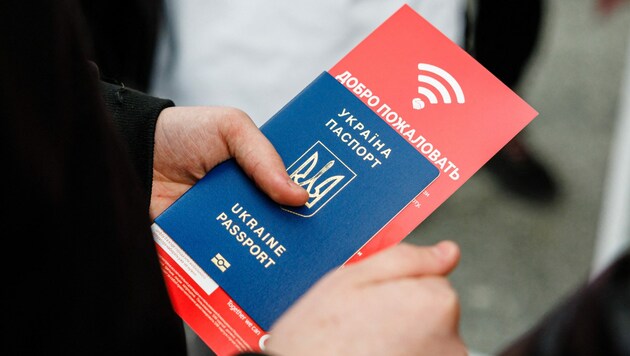 Ein ukrainischer Flüchtling hält bei seiner Ankunft am Hauptbahnhof Dresden einen Reisepass und einen Flyer für Handy-SIM-Karten in der Hand. (Bild: AFP)
