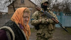 Diese betagte Ukrainerin aus Motyschyn wartet unter dem Schutz eines Soldaten auf die Essensausgabe. (Bild: AP)