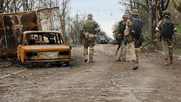 Soldaten der Miliz der Volksrepublik Donezk gehen während schwerer Kämpfe in einem von den von Russland unterstützten Separatisten kontrollierten Gebiet in Mariupol an beschädigten Fahrzeugen vorbei. (Bild: The Associated Press)