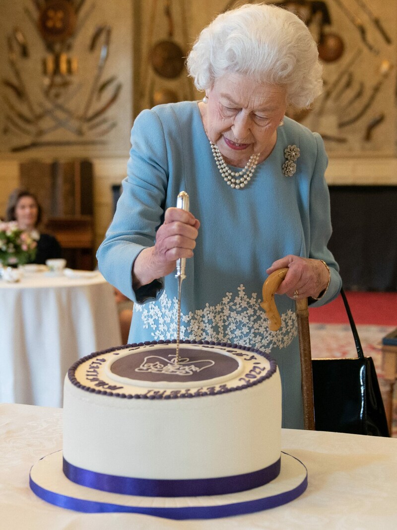 Queen Elizabeth II. schneidet die Torte an. (Bild: APA/Photo by Joe Giddens/AFP))