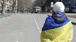 Eine Frau mit ukrainischer Flagge steht während einer Kundgebung gegen die russische Besatzung in Cherson vor russischen Truppen auf der Straße. (Bild: ASSOCIATED PRESS)