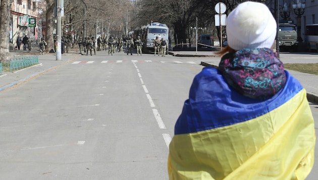 Eine Ukrainerin steht russischen Soldaten gegenüber. (Bild: AP)