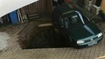 Ein in der Hofeinfahrt geparkter VW Golf blieb an der Oberfläche hängen, da er auf einem Kanalschacht geparkt war. (Bild: Landratsamt/ Freiwillige Feuerwehr Neukirchen am Teisenberg)