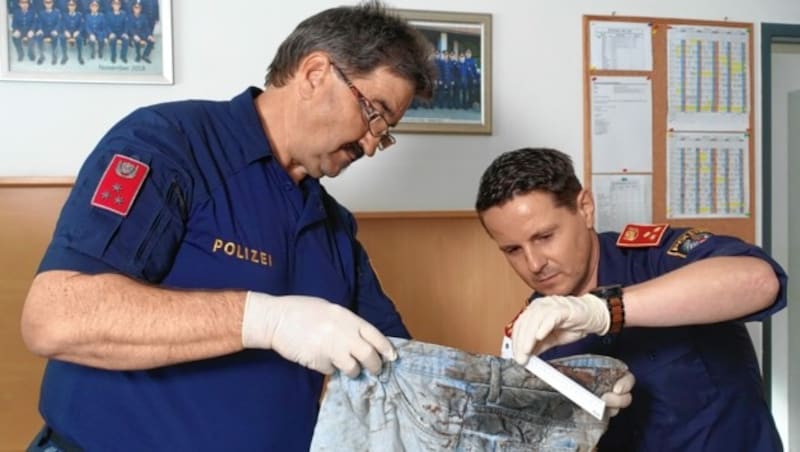 Michael Seisser und Markus Haas von der Polizeiinspektion Neumark untersuchen die Kleidung des Unfallopfers. Sie kommen auch am 12. 5. bei „Fahndung Österreich“ zu Wort. (Bild: ServusTV / Mabon Film)