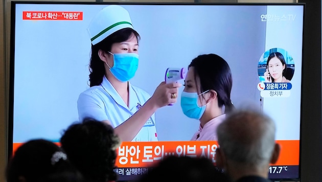 Passanten im südkoreanischen Seoul verfolgen auf einem Fernsehbildschirm einen Nachrichtenbericht über den Covid-19-Ausbruch im benachbarten Nordkorea. (Bild: AP)