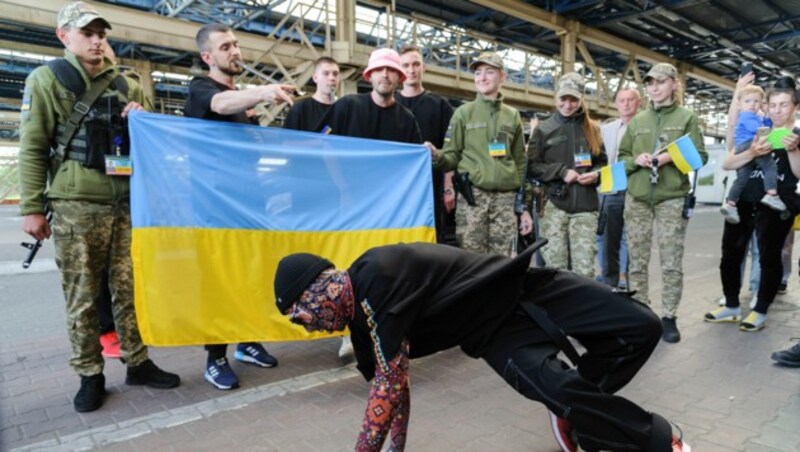 Das Kalush Orchestra musiziert und tanzt an der ukrainischen Grenze mit ukrainischen Grenzsoldaten, die die ukrainische Flagge halten. (Bild: APA/AP Photo/Mykola Tys)