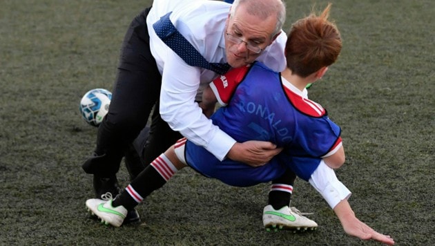 Australiens Premier Scott Morrison ging in Anzug und Krawatte auf „Tuchfühlung“ mit einem jungen Sportler. Beide überstanden die Einlage unbeschadet. (Bild: Mick Tsikas/AAP Image via AP)