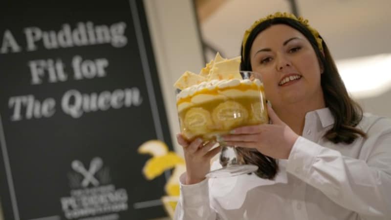 Jemma Melvin zeigt ihren Zitronen-Amaretto-Trifle in die Kamera, mit dem sie den königlichen Jubiläums-Nachtisch-Wettbewerb gewonnen hat. (Bild: APA/AP Photo/Alastair Grant)