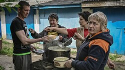 Bewohner der Stadt Lyssytschansk kochen Essen außerhalb ihrer Häuser. (Bild: APA/AFP/ARIS MESSINIS)