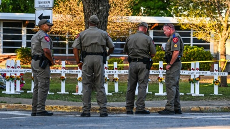 Polizisten bei der improvisierten Gedenkstätte für die ermordeten Schüler (Bild: APA/AFP/CHANDAN KHANNA)