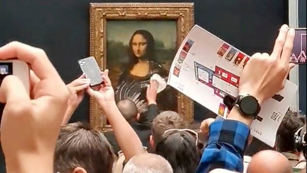 Der Tortenwerfer hatte sich als Frau verkleidet. Mit Perücke und im Rollstuhl fuhr er vor das Kunstwerk und warf anschließend die Torte auf die „Mona Lisa“, bevor er von Sicherheitspersonal hinausbegleitet wurde. (Bild: AP/@Klevisl007)