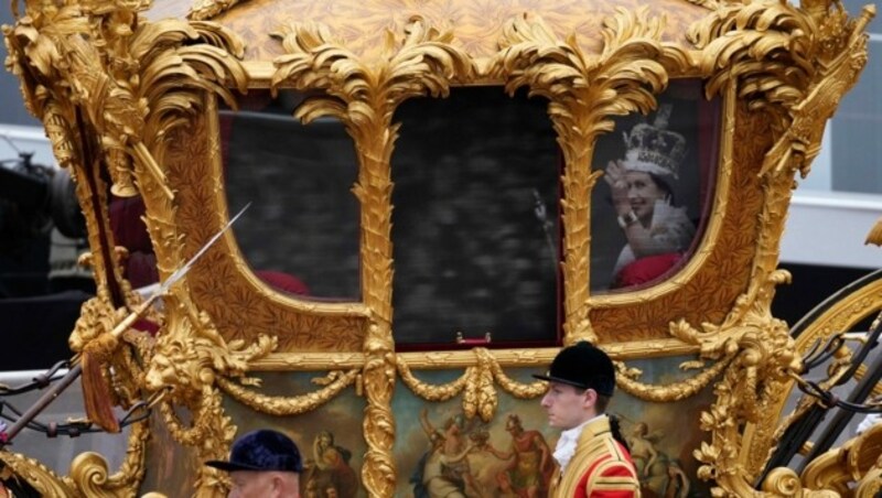 Aus der 260 Jahre alten goldene Staatskutsche winkt ein Hologramm der Queen. (Bild: APA/Photo by Frank Augstein/AFP)