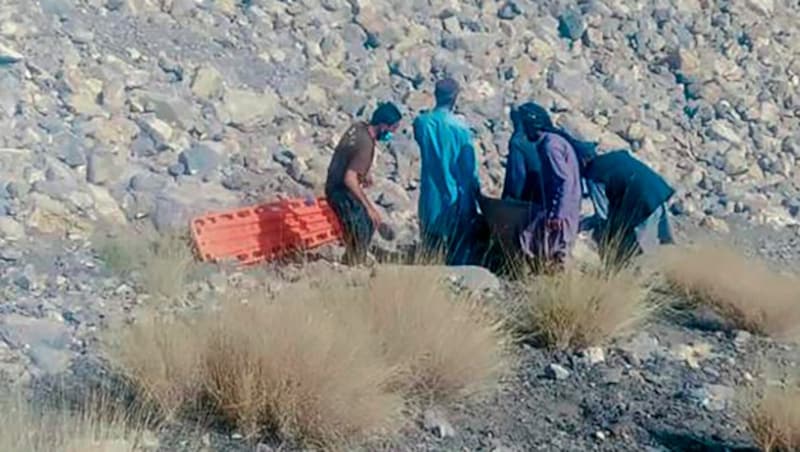 Rettungskräfte und freiwillige Helfer bergen ein Opfer des Busunglücks. (Bild: Associated Press)