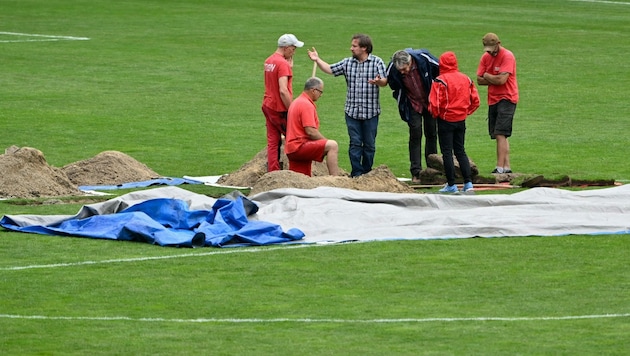 Das Loch im Stadion-Rasen wird untersucht und „gestopft“. (Bild: APA/HELMUT FOHRINGER)