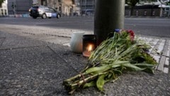 Kerzen und ein Blumenstrauß liegen auf dem Bürgersteig an der Tauentzienstraße. (Bild: APA/dpa/Fabian Sommer)