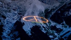 Greenpeace erregt Aufmerksamkeit beim G7-Gipfel: erst ein 60 Meter großes Peace-Zeichen aus brennenden Kerzen in einer Felswand bei Garmisch-Partenkirchen, dann ein Schriftzug am Waxenstein (Bild: Copyright 2022 The Associated Press. All rights reserved)