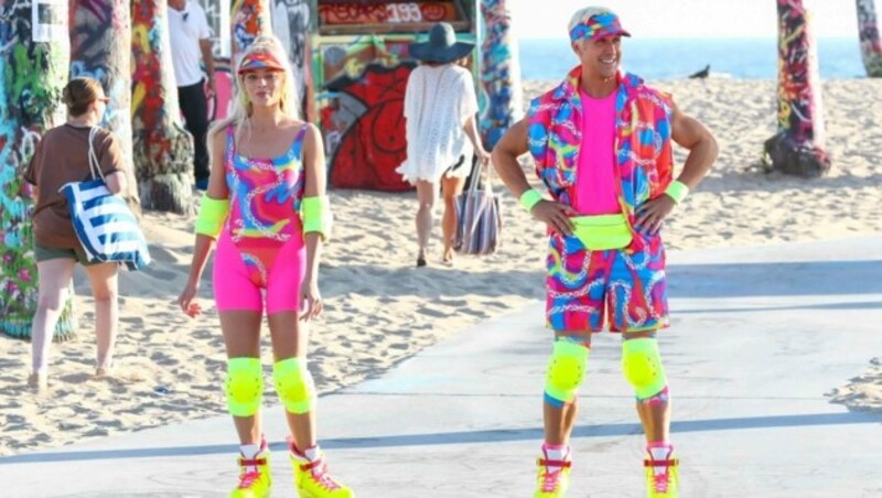 Margot Robbie und Ryan Gosling lachen gemeinsam, als sie in Venice Beach eine Rollerblading-Szene für „Barbie“ in sehr bunter Neonkleidung drehen. (Bild: www.PPS.at)