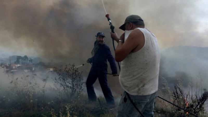 Freiwillige Helfer versuchen zu verhindern, dass ein Waldbrand auf die Häuser in dem Dorf Casal da Quinta außerhalb von Leiria in Zentralportugal übergreift. (Bild: ASSOCIATED PRESS)