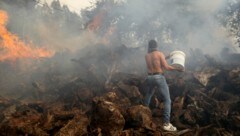 Ein Anwohner versucht mit einem Eimer zu verhindern, dass ein Waldbrand auf Häuser im Dorf Figueiras übergreift. (Bild: Copyright 2022 The Associated Press. All rights reserved)