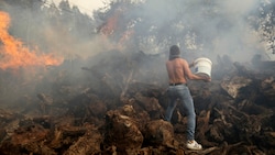Ein Anwohner versucht mit einem Eimer zu verhindern, dass ein Waldbrand auf Häuser im Dorf Figueiras übergreift. (Bild: Copyright 2022 The Associated Press. All rights reserved)
