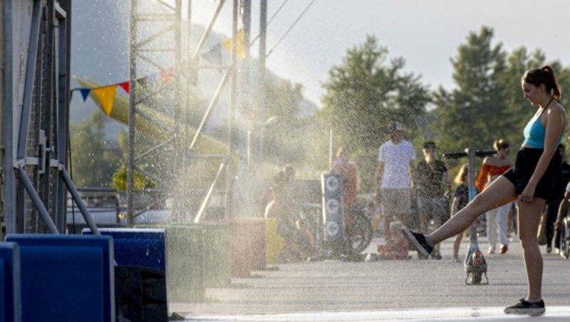 Eine Frau sucht Abkühlung im Sprühnebel auf der Donauinsel. (Bild: APA/Tobias Steinmaurer)