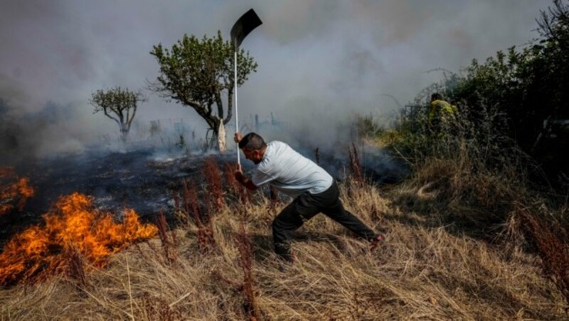 Ein Anrainer versucht in Tabara, im Nordwesten von Spanien die Ausbreitung eines Feuers zu stoppen. S (Bild: Associated Press)