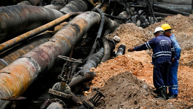 Mitarbeiter des Treibstofflagers begutachten die Schäden. (Bild: APA/AFP/Yamil LAGE)