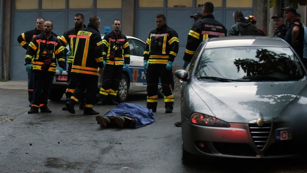 Feuerwehrleute stehen neben einer Leiche am Ort des Anschlags in Cetinje, etwa 30 km westlich von Podgorica, (Bild: The Associated Press)