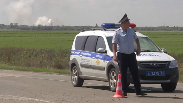 Ein Polizist versperrt den Weg zum Ort der Explosion in einem Munitionslager der russischen Armee in der Nähe des Dorfes Mayskoje auf der Krim. (Bild: AP)
