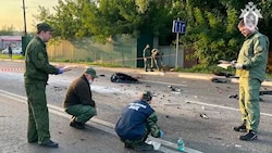 Russische Behördenvertreter untersuchen die Überbleibsel des explodierten Autos. (Bild: AP/Investigative Committee of Russia)