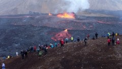 Besucher und Besucherinnen sehen sich die Lavaströme des Vulkans auf Island an. (Bild: AFP)