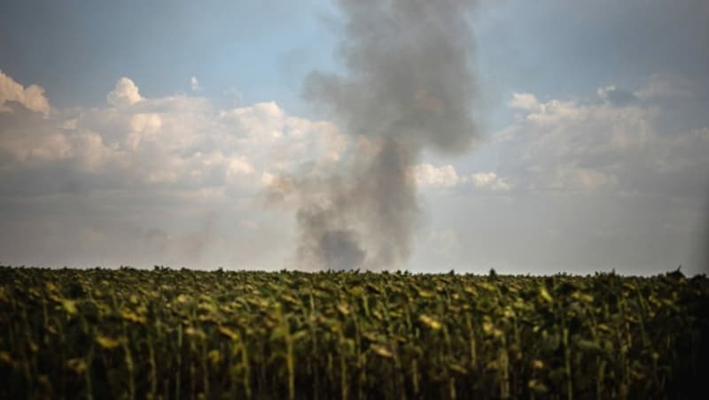 Über einem Sonnenblumenfeld im Süden der Ukraine steigt schwarzer Rauch auf. In dem Gebiet hat das ukrainische Militär eine Gegenoffensive gestartet. (Bild: APA/AFP/Dimitar DILKOFF)