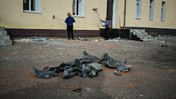 Arbeiter reinigen die Fassade eines beschädigten Schulgebäudes nach einem Raketeneinschlag in Charkiw. (Bild: AFP)