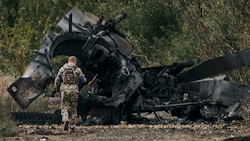 Ein ukrainischer Soldat vor einem zerstörten russischen Panzer im Gebiet Charkiw (Bild: AP)
