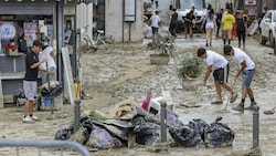 Menschen beim Aufräumen nach den schweren Unwettern in Italien (Bild: LaPresse/AFP)