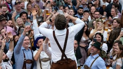 Ein Mann trinkt ein Bier und wird im Hofbräu-Zelt von der Menge angefeuert. (Bild: APA/dpa/Sven Hoppe)