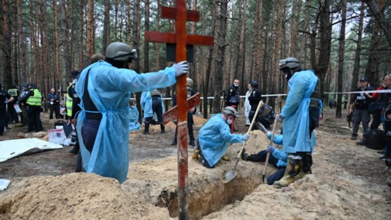 Forensiker exhumieren die in einem Wald bei Isjum entdeckten Leichen. (Bild: APA/AFP/SERGEY BOBOK)