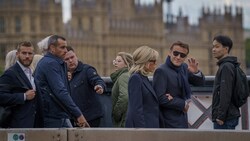 Der französische Präsident Emmanuel Macron winkt, während er und seine Frau Brigitte Macron über eine Brücke zum Palast von Westminster gehen, um Queen Elizabeth die letzte Ehre zu erweisen. (Bild: APA/Photo by Heiko Junge/NTB/AFP)