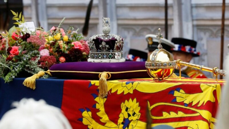 Der Sarg von Königin Elisabeth II. st neben der königlichen Standarte, der Königskrone, dm Reichsapfel und Zepter des Souveräns mit einem Brief von Köngi Charles geschmückt. (Bild: APA/Photo by Tristan Fewings/AFP)