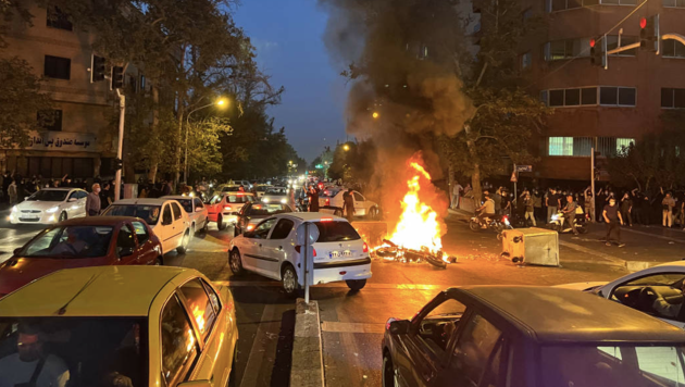 Bei den Protesten wurde ein Polizeimotorrad in Brand gesetzt. (Bild: ASSOCIATED PRESS)