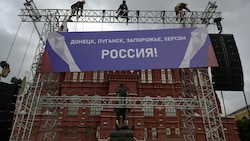 Arbeiter befestigen ein Transparent mit der Aufschrift „Donezk, Lugansk, Saporischschja, Cherson - Russland“ auf dem Roten Platz im Zentrum Moskaus. Russland hat am vergangenen Freitag in einer großen Zeremonie vier von seinen Truppen besetzte Regionen der Ukraine formell annektiert. (Bild: AFP)