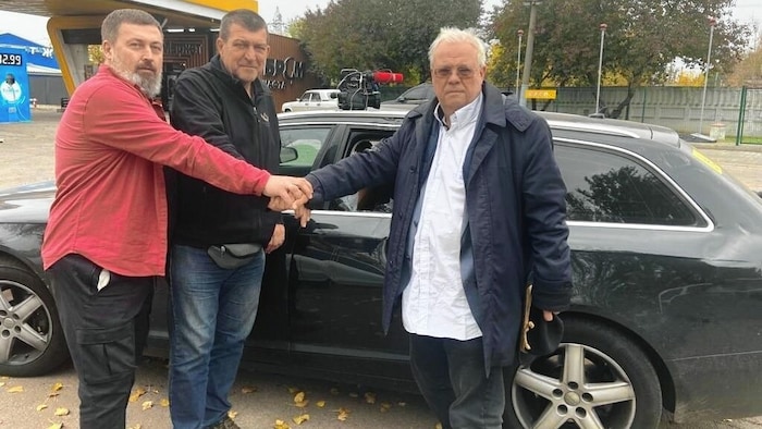 Wehrschütz (re.) und seine Mitarbeiter vor dem beschädigten Auto