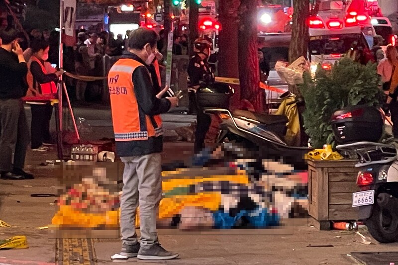 Zahlreiche junge Menschen lagen mit Tüchern bedeckt auf der Straße. Viele von ihnen sollen erdrückt worden sein. (Bild: AFP or licensors, Krone KREATIV)